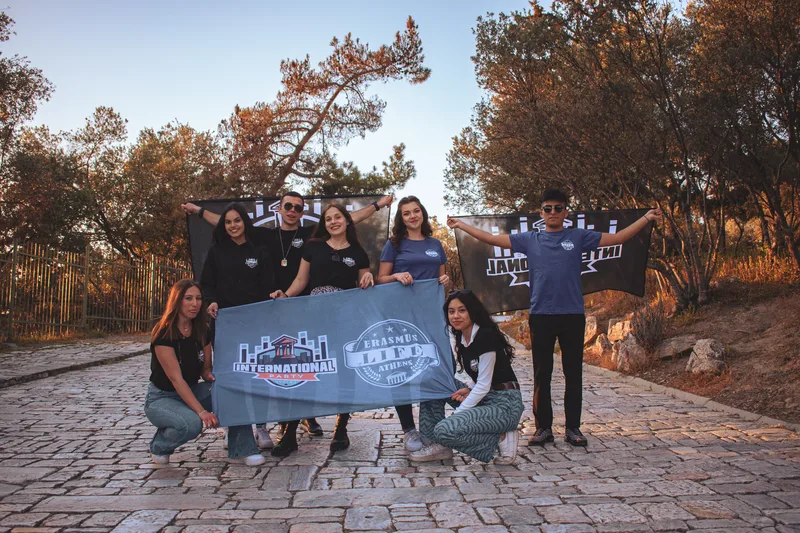 The Erasmus Life Athens crew on Philopappou Hill, holding the banners at golden hour